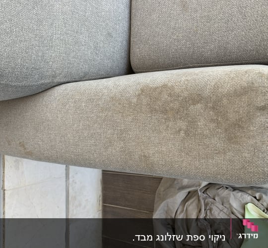 כרית ספה אפורה עם כתמים, כפפה ירוקה ובד על הרצפה